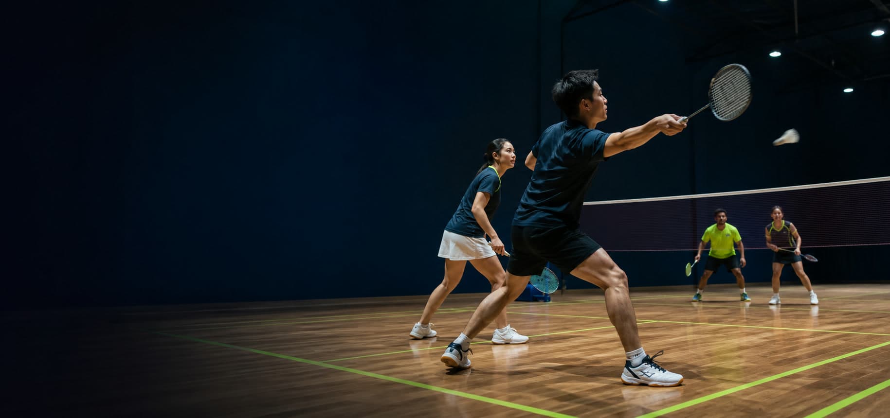 Badminton players rallying on an indoor court